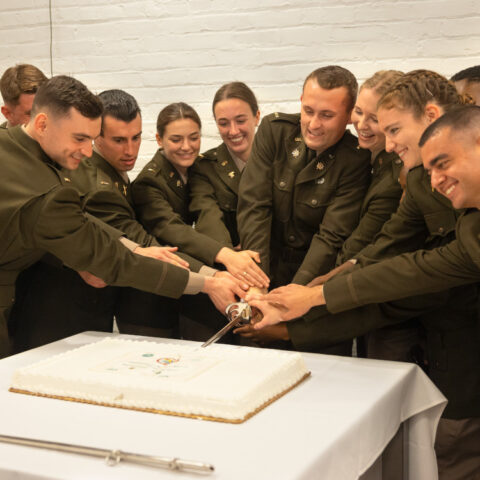 Newly commissioned army reserve graduates cut their ceremonial cake at the 2022 ROTC Commisisoning Ceremony in the Alice Statler Auditorium.